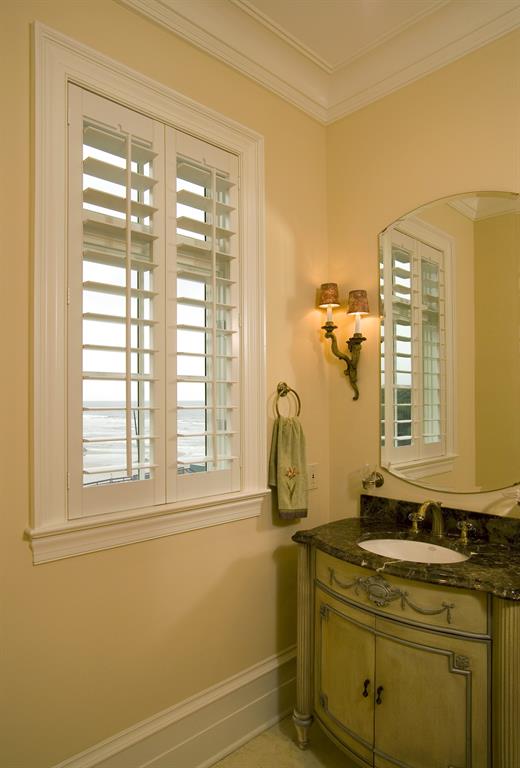White plantation shutters in a bathroom outlooking the ocean